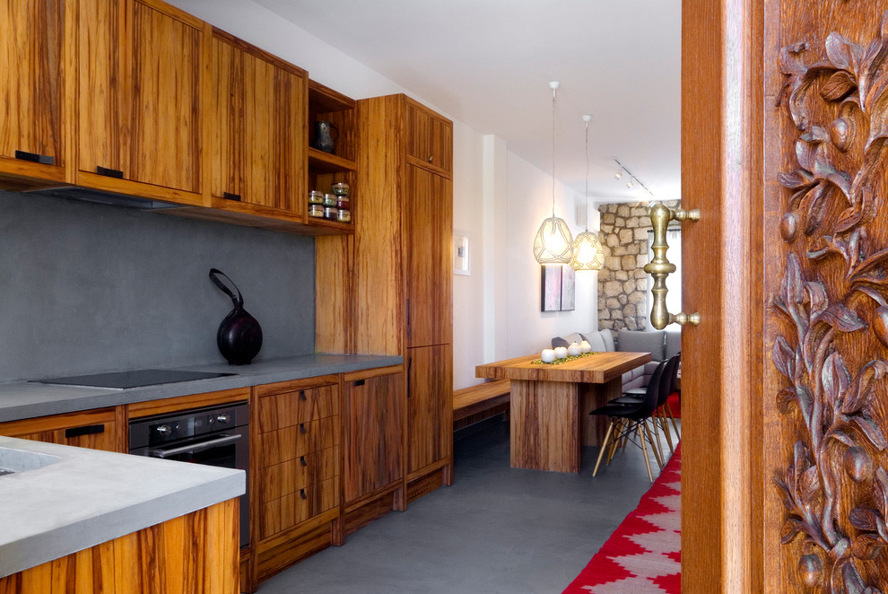 Exemple d'une cuisine ouverte encastrable montagne en L et bois brun avec un placard à porte plane, un plan de travail en béton et une crédence grise.