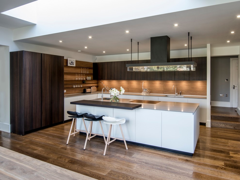 Moderne Küche in L-Form mit Unterbauwaschbecken, flächenbündigen Schrankfronten, weißen Schränken, braunem Holzboden und Kücheninsel in London