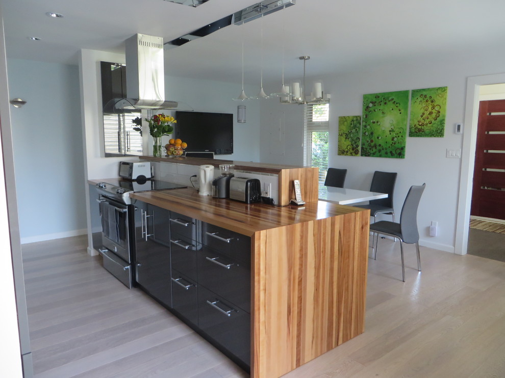 Photo of a medium sized contemporary galley kitchen/diner in Vancouver with a double-bowl sink, flat-panel cabinets, grey cabinets, wood worktops, white splashback, stone slab splashback and an island.