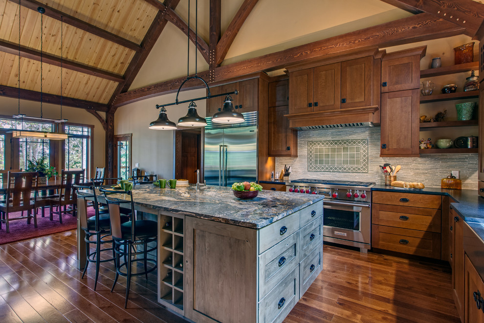 Inspiration for a large craftsman u-shaped medium tone wood floor and brown floor eat-in kitchen remodel in Nashville with a farmhouse sink, shaker cabinets, medium tone wood cabinets, granite countertops, gray backsplash, matchstick tile backsplash, stainless steel appliances, an island and multicolored countertops