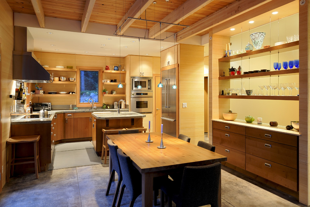 Foto på ett mellanstort funkis kök, med en undermonterad diskho, släta luckor, skåp i ljust trä, granitbänkskiva, rostfria vitvaror, betonggolv, en köksö och grått golv