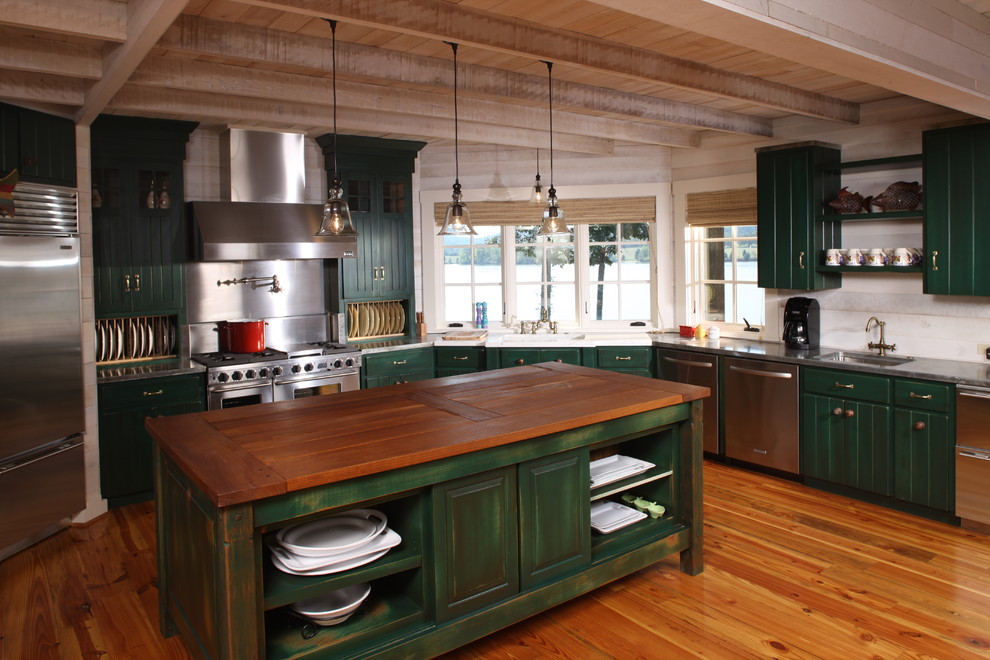 Example of a large country u-shaped dark wood floor enclosed kitchen design in Other with an undermount sink, louvered cabinets, green cabinets, wood countertops, beige backsplash, stainless steel appliances and an island
