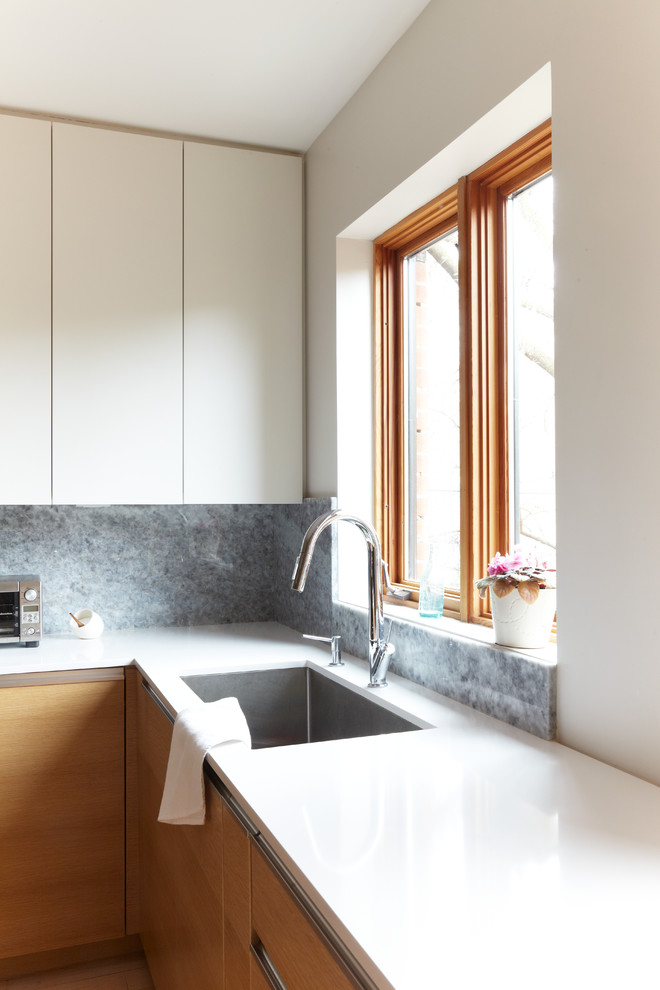 Inspiration for a mid-sized modern l-shaped eat-in kitchen remodel in Toronto with an undermount sink, flat-panel cabinets, white cabinets, gray backsplash and cement tile backsplash