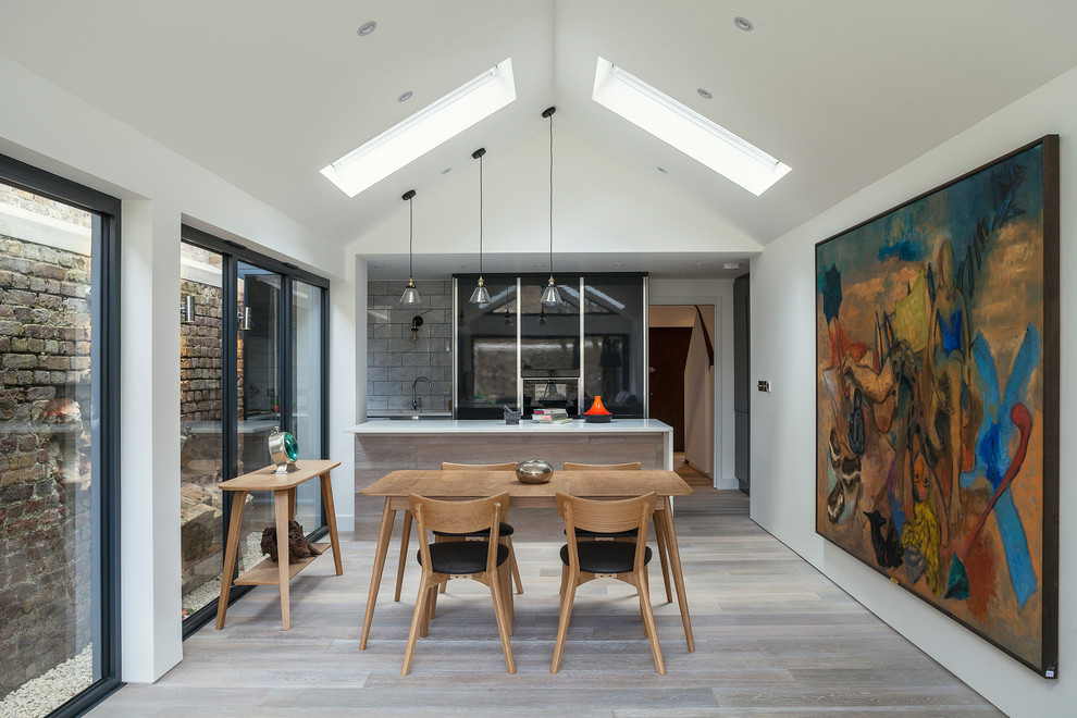 Contemporary kitchen/diner in London with light hardwood flooring and a breakfast bar.