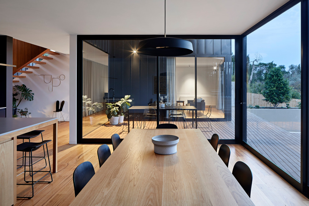 Immagine di una grande sala da pranzo aperta verso la cucina minimalista con parquet chiaro