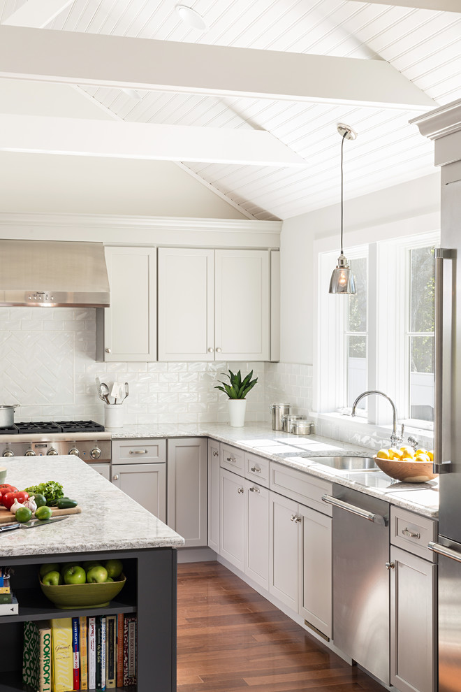 Inspiration for a mid-sized contemporary l-shaped medium tone wood floor open concept kitchen remodel in Boston with an undermount sink, recessed-panel cabinets, gray cabinets, quartz countertops, white backsplash, subway tile backsplash, stainless steel appliances and an island