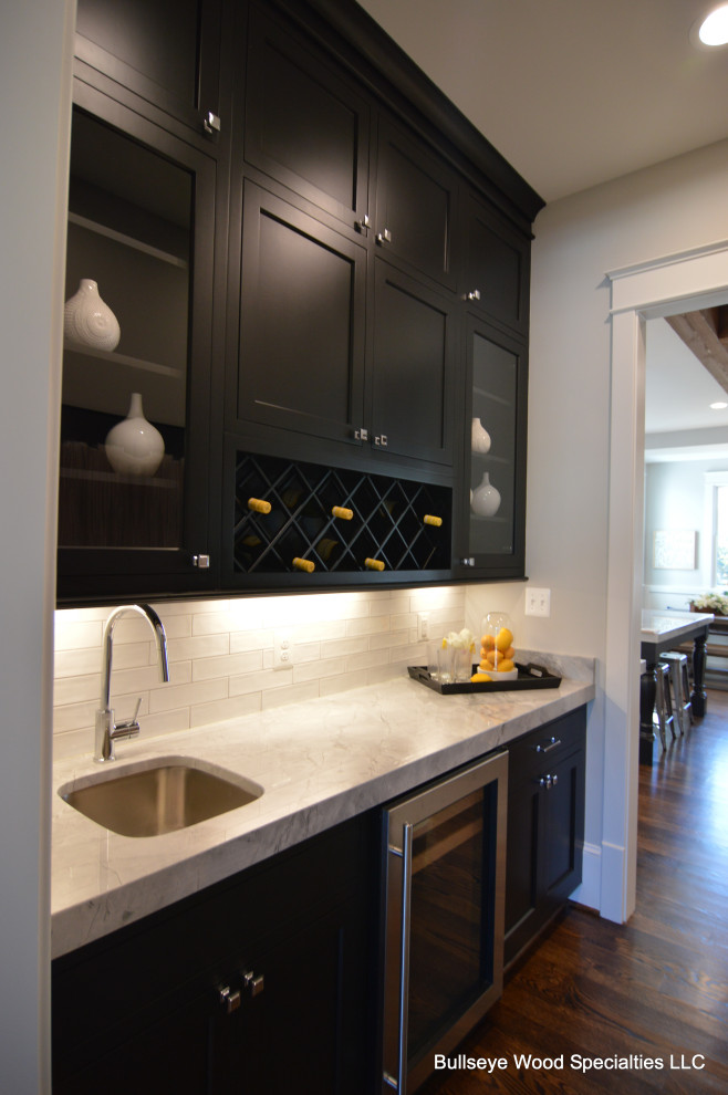 Photo of a large traditional single-wall kitchen pantry in DC Metro with a single-bowl sink, shaker cabinets, black cabinets, granite worktops, white splashback, metro tiled splashback, integrated appliances, dark hardwood flooring, brown floors and grey worktops.