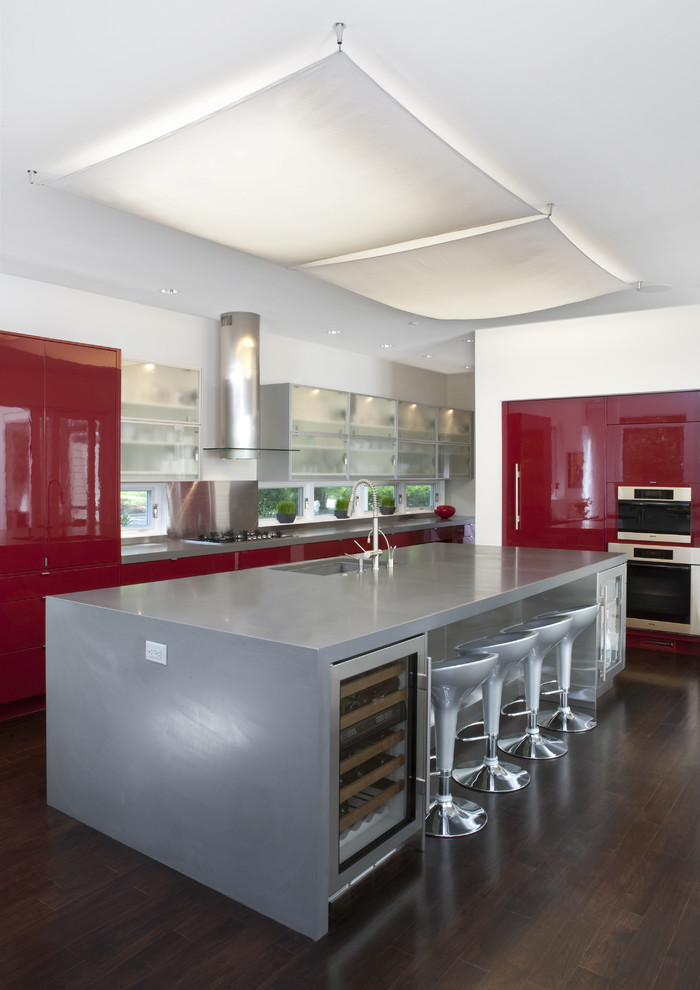 Exempel på ett stort klassiskt grå grått kök och matrum, med rostfria vitvaror, släta luckor, röda skåp, bänkskiva i betong, en undermonterad diskho, mörkt trägolv och en köksö