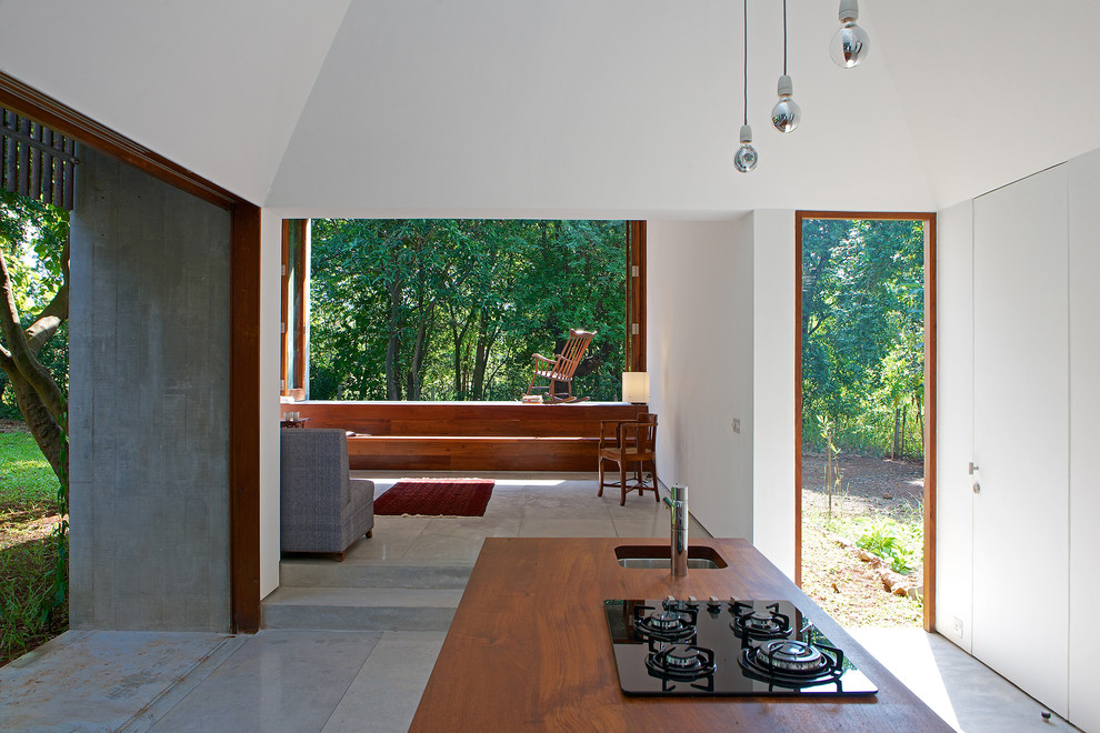 Ejemplo de cocina minimalista de tamaño medio con fregadero bajoencimera, encimera de madera, electrodomésticos negros, suelo de terrazo y una isla