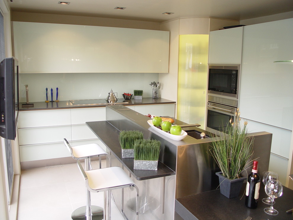 Exempel på ett avskilt, mellanstort modernt l-kök, med en enkel diskho, släta luckor, vita skåp, rostfria vitvaror och en köksö