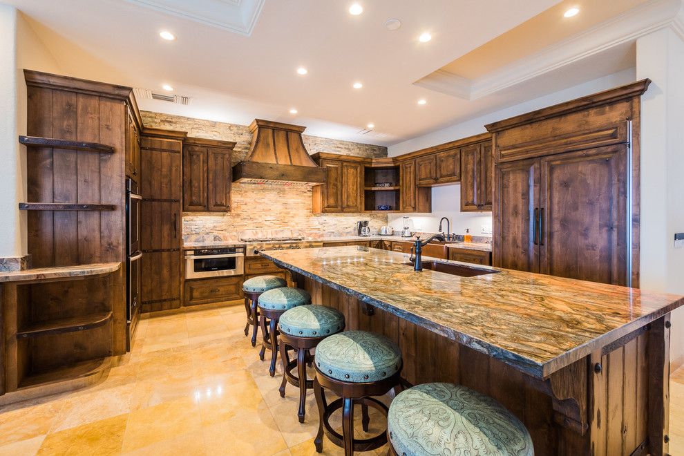 Large rustic u-shaped kitchen/diner in Mexico City with a belfast sink, brown cabinets, granite worktops, multi-coloured splashback, stone slab splashback, stainless steel appliances, travertine flooring and an island.