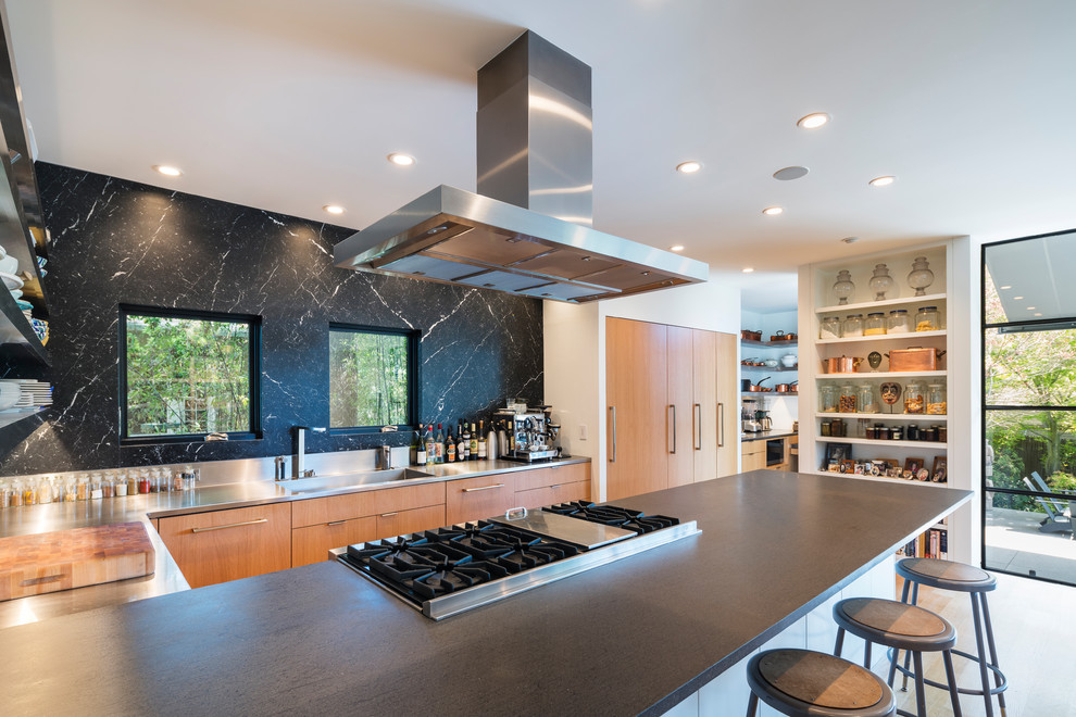 Exempel på ett mellanstort modernt grå grått kök, med en integrerad diskho, släta luckor, skåp i mellenmörkt trä, stänkskydd med metallisk yta, rostfria vitvaror, en köksö, beiget golv, bänkskiva i täljsten och ljust trägolv