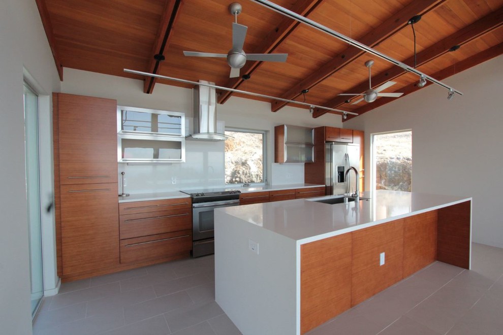Inspiration for a large modern single-wall kitchen/diner in Hawaii with a submerged sink, flat-panel cabinets, medium wood cabinets, engineered stone countertops, white splashback, stainless steel appliances, ceramic flooring, an island and glass sheet splashback.