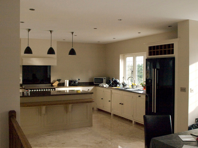 Photo of a large classic l-shaped open plan kitchen in Manchester with a built-in sink, white cabinets, black appliances, marble flooring, an island, beige floors and beaded cabinets.