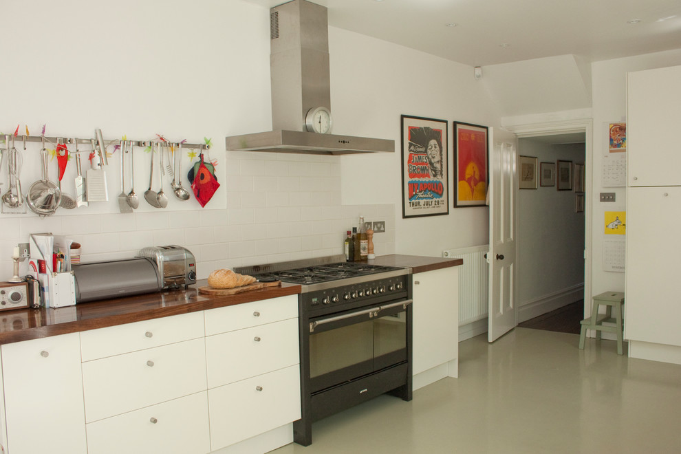 Contemporary kitchen in Other with flat-panel cabinets, white cabinets, wood worktops, white splashback, metro tiled splashback and black appliances.