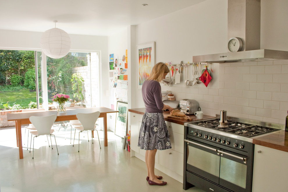 Foto di una cucina abitabile minimal con ante lisce, ante bianche, top in legno, paraspruzzi bianco, paraspruzzi con piastrelle diamantate e elettrodomestici neri