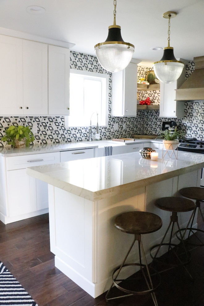 Photo of a medium sized eclectic l-shaped enclosed kitchen in St Louis with a belfast sink, shaker cabinets, white cabinets, marble worktops, multi-coloured splashback, ceramic splashback, stainless steel appliances, dark hardwood flooring, an island, brown floors and white worktops.