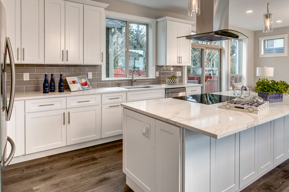 Inspiration for a mid-sized timeless l-shaped light wood floor and beige floor eat-in kitchen remodel in Seattle with an undermount sink, shaker cabinets, white cabinets, quartz countertops, gray backsplash, glass tile backsplash, stainless steel appliances, an island and white countertops