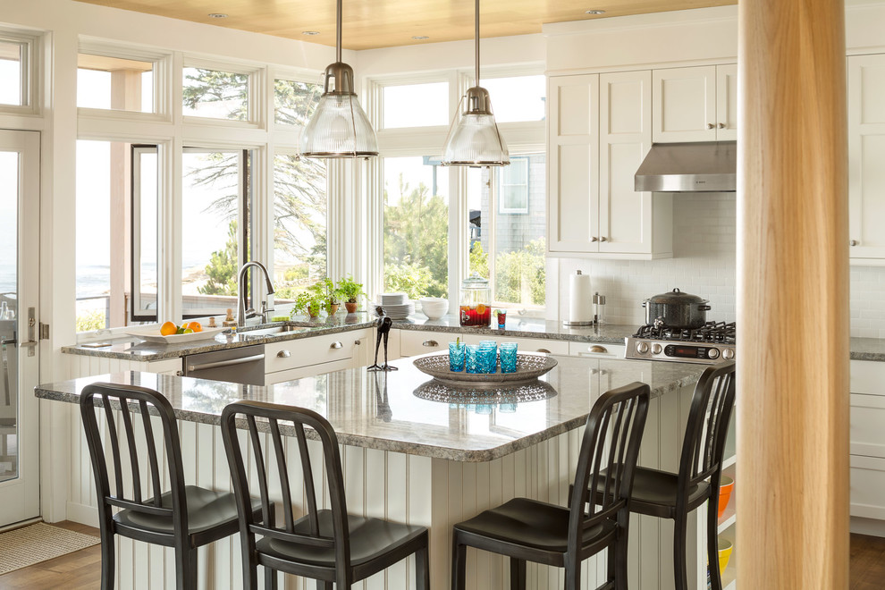 Maritime Küche in L-Form mit Kücheninsel, Unterbauwaschbecken, Schrankfronten mit vertiefter Füllung, weißen Schränken, Küchengeräten aus Edelstahl, braunem Holzboden und Holzdecke in Portland Maine