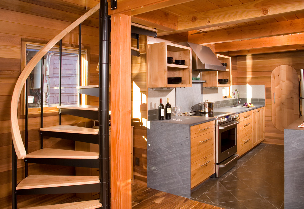 Bild på ett rustikt kök, med släta luckor, rostfria vitvaror, grått stänkskydd, stänkskydd i stenkakel, granitbänkskiva och kalkstensgolv