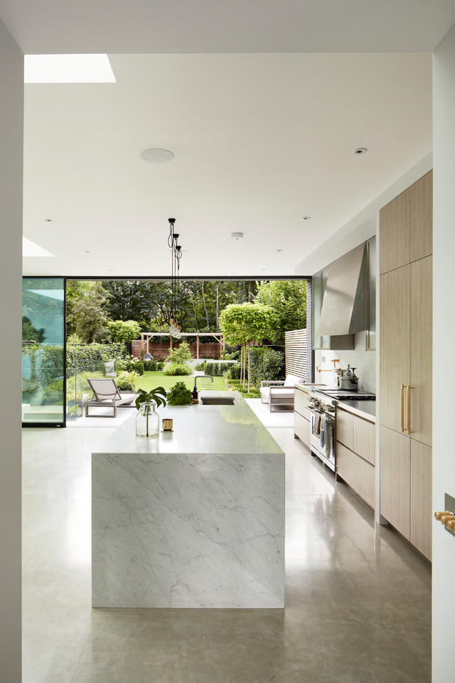 Idéer för ett mellanstort modernt linjärt kök, med en undermonterad diskho, släta luckor, skåp i ljust trä, marmorbänkskiva, vitt stänkskydd, stänkskydd i marmor, rostfria vitvaror, betonggolv, en köksö och grått golv