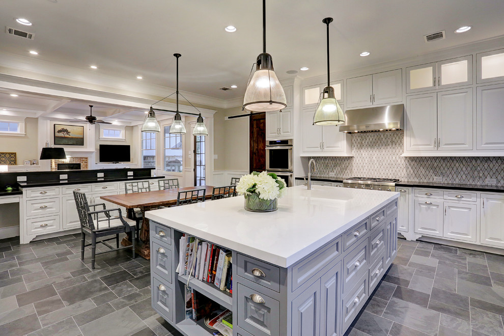 Klassisk inredning av ett stort kök, med luckor med upphöjd panel, vita skåp, en köksö, granitbänkskiva, stänkskydd i marmor, rostfria vitvaror, travertin golv och grått golv