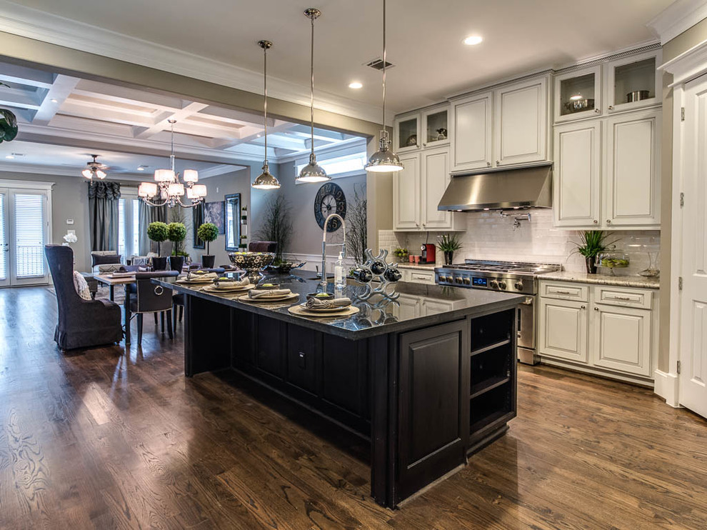 Example of a mid-sized arts and crafts l-shaped dark wood floor and brown floor eat-in kitchen design in Houston with an undermount sink, raised-panel cabinets, white cabinets, granite countertops, white backsplash, ceramic backsplash, stainless steel appliances and an island