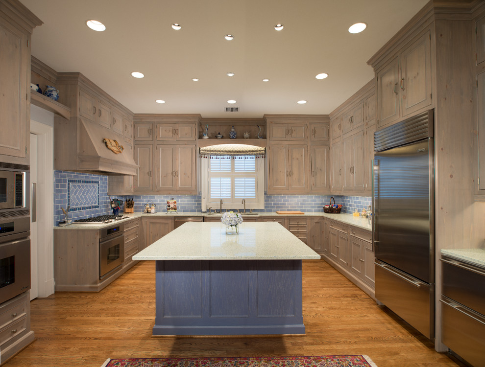 Foto på ett stort rustikt kök, med en nedsänkt diskho, skåp i mellenmörkt trä, marmorbänkskiva, blått stänkskydd, stänkskydd i keramik, rostfria vitvaror, mellanmörkt trägolv, en köksö och luckor med infälld panel