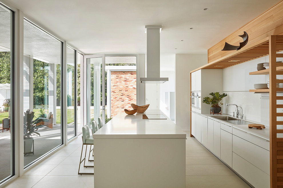 Immagine di una cucina minimalista con lavello da incasso, ante lisce, ante bianche, paraspruzzi bianco, paraspruzzi in lastra di pietra, pavimento beige e top bianco