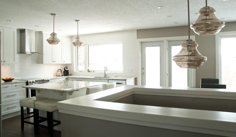 Klassische Küche mit weißen Schränken, Küchenrückwand in Weiß, Küchengeräten aus Edelstahl, Kücheninsel und braunem Boden in Sonstige