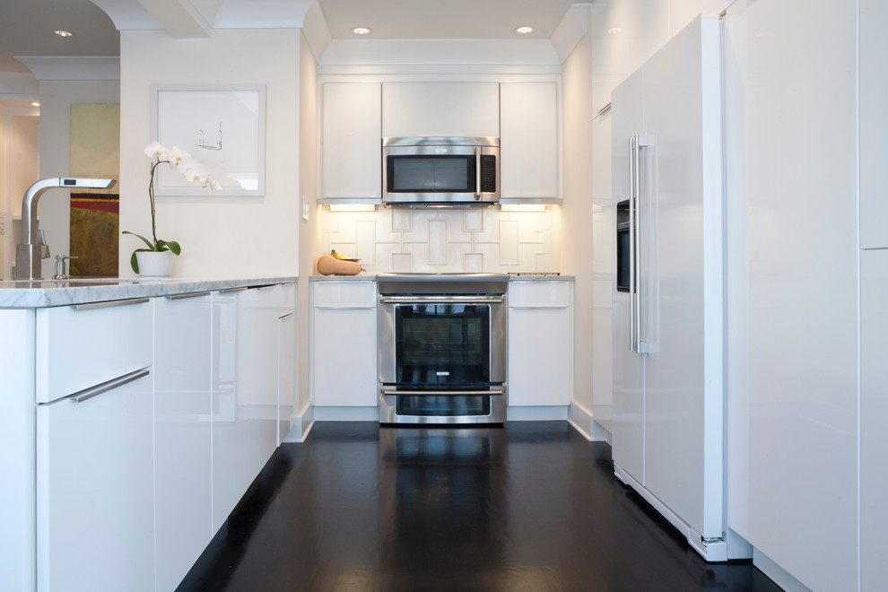 Exempel på ett litet modernt kök, med en enkel diskho, släta luckor, vita skåp, marmorbänkskiva, vitt stänkskydd, stänkskydd i porslinskakel, integrerade vitvaror, mörkt trägolv, en halv köksö och brunt golv