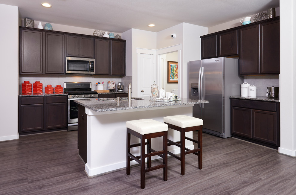 Example of a large transitional l-shaped medium tone wood floor and gray floor eat-in kitchen design in Houston with a double-bowl sink, recessed-panel cabinets, dark wood cabinets, granite countertops, white backsplash, subway tile backsplash, stainless steel appliances and an island