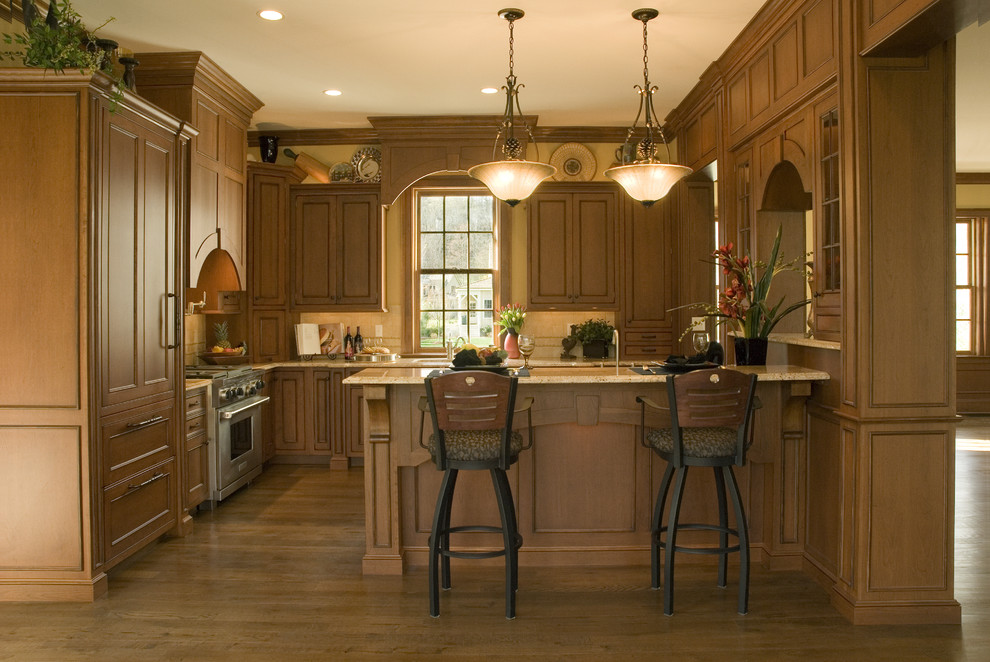 Inspiration for a mid-sized timeless u-shaped medium tone wood floor and brown floor enclosed kitchen remodel in Huntington with an undermount sink, recessed-panel cabinets, medium tone wood cabinets, granite countertops, beige backsplash, stone tile backsplash, paneled appliances and a peninsula
