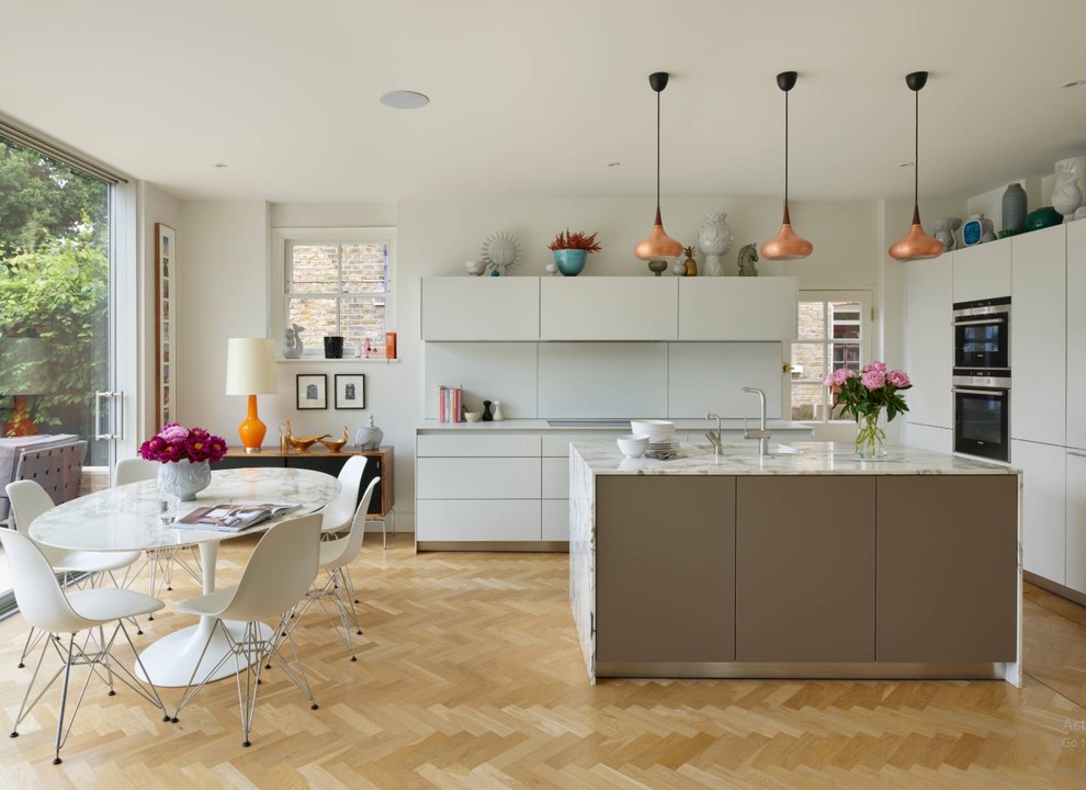 Design ideas for a large modern l-shaped kitchen/diner in London with a double-bowl sink, flat-panel cabinets, grey cabinets, composite countertops, light hardwood flooring, an island, beige floors and grey worktops.