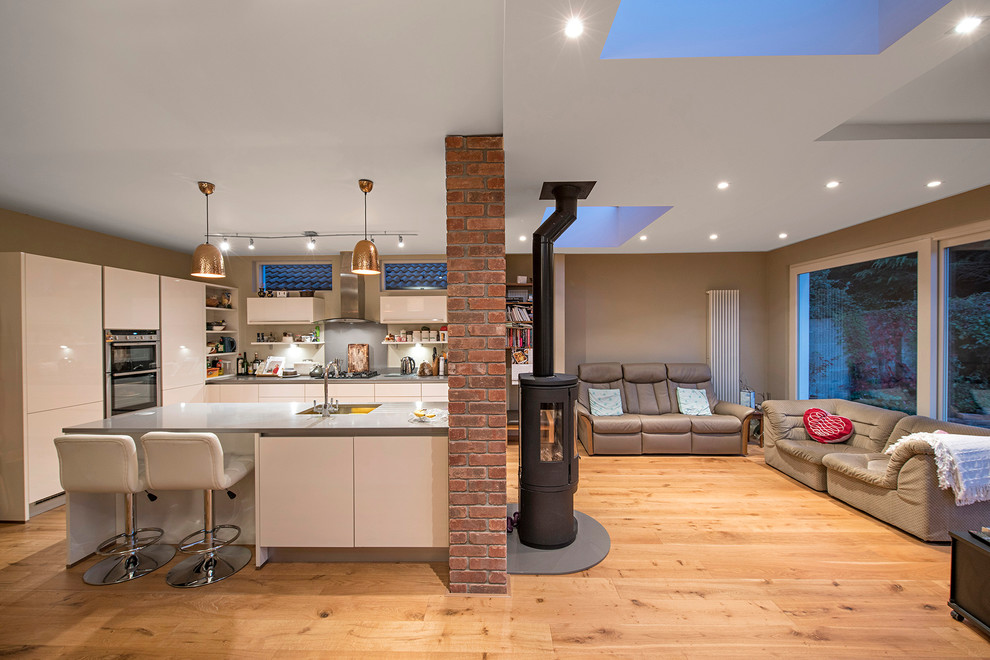 Offene Moderne Küche mit Waschbecken, flächenbündigen Schrankfronten, weißen Schränken, Küchenrückwand in Grau, Küchengeräten aus Edelstahl und hellem Holzboden in Dublin