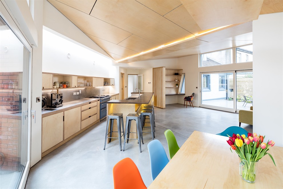 На фото: параллельная кухня-гостиная в стиле ретро с плоскими фасадами, светлыми деревянными фасадами, бетонным полом и островом с