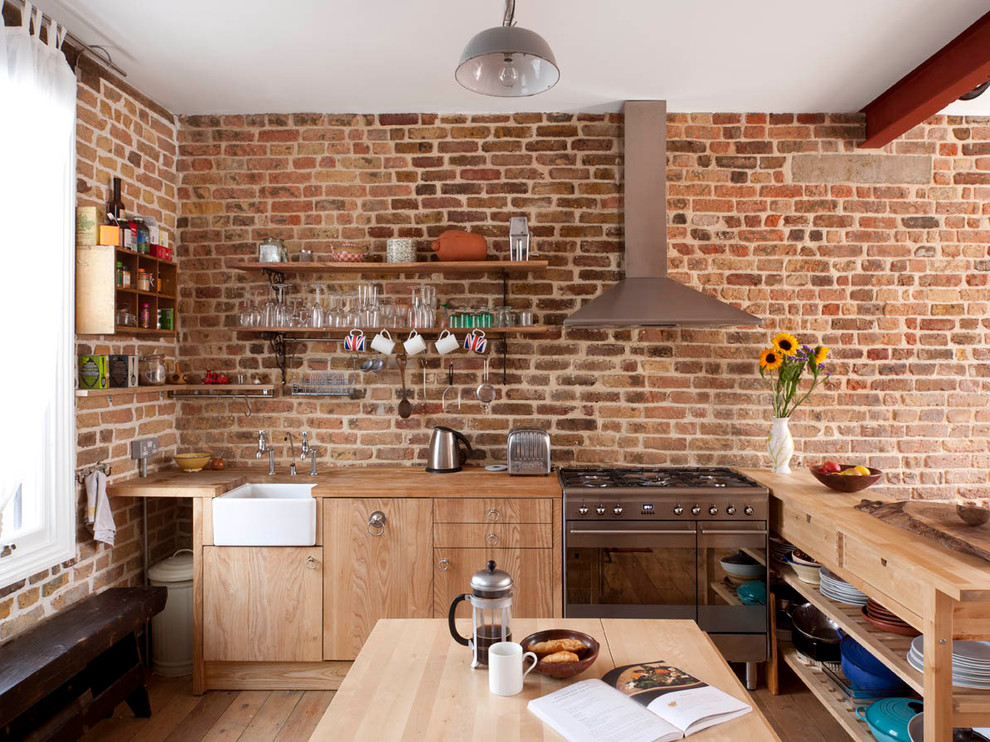 Foto på ett industriellt l-kök, med en rustik diskho, släta luckor, skåp i ljust trä, rostfria vitvaror, ljust trägolv och en köksö