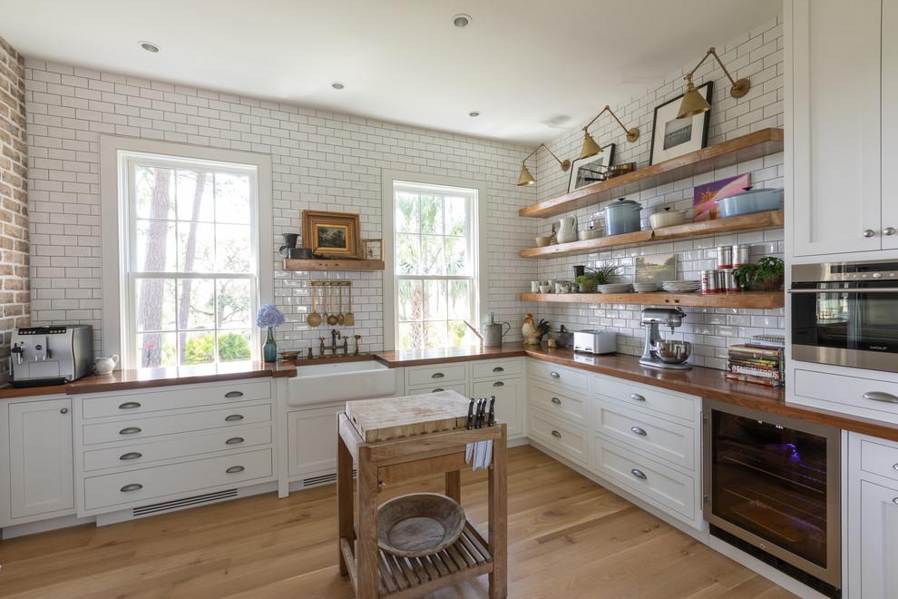 Inspiration for a large timeless u-shaped light wood floor kitchen pantry remodel in Charleston with a single-bowl sink, shaker cabinets, white cabinets, wood countertops, white backsplash, subway tile backsplash, stainless steel appliances and an island