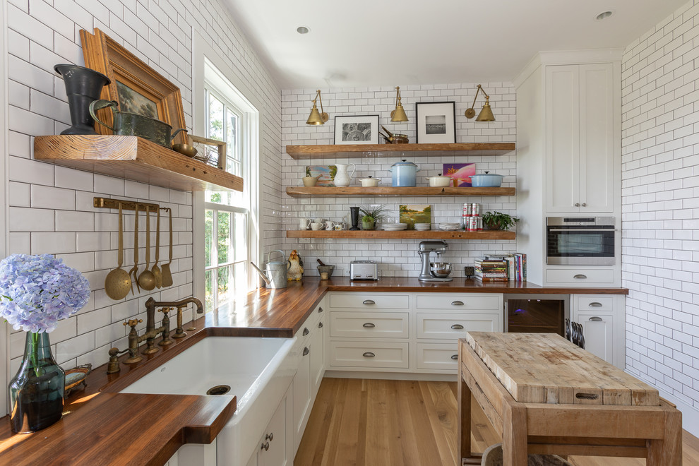 Kitchen pantry - large traditional u-shaped light wood floor kitchen pantry idea in Charleston with a single-bowl sink, shaker cabinets, white cabinets, wood countertops, white backsplash, subway tile backsplash, stainless steel appliances and an island
