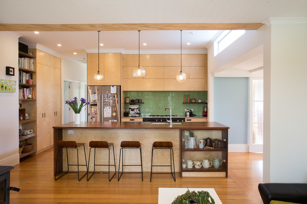 Mid-sized trendy galley light wood floor kitchen photo in Auckland with a double-bowl sink, light wood cabinets, green backsplash, ceramic backsplash, stainless steel appliances, an island and multicolored countertops