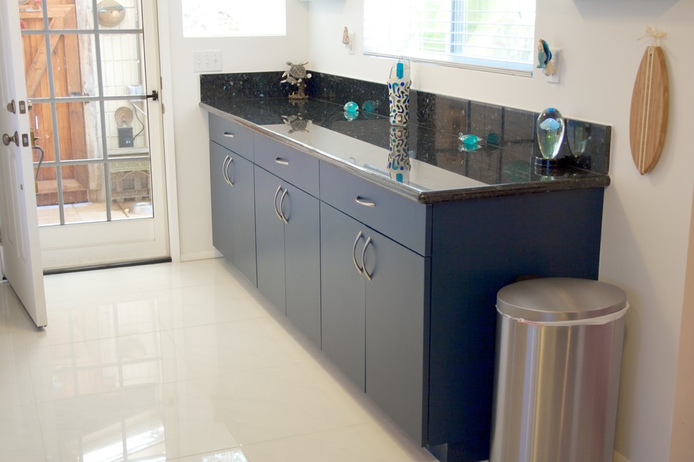 Kleine Moderne Küche in U-Form mit Einbauwaschbecken, flächenbündigen Schrankfronten, blauen Schränken, Küchenrückwand in Schwarz, Küchengeräten aus Edelstahl, Keramikboden und Granit-Arbeitsplatte in Hawaii