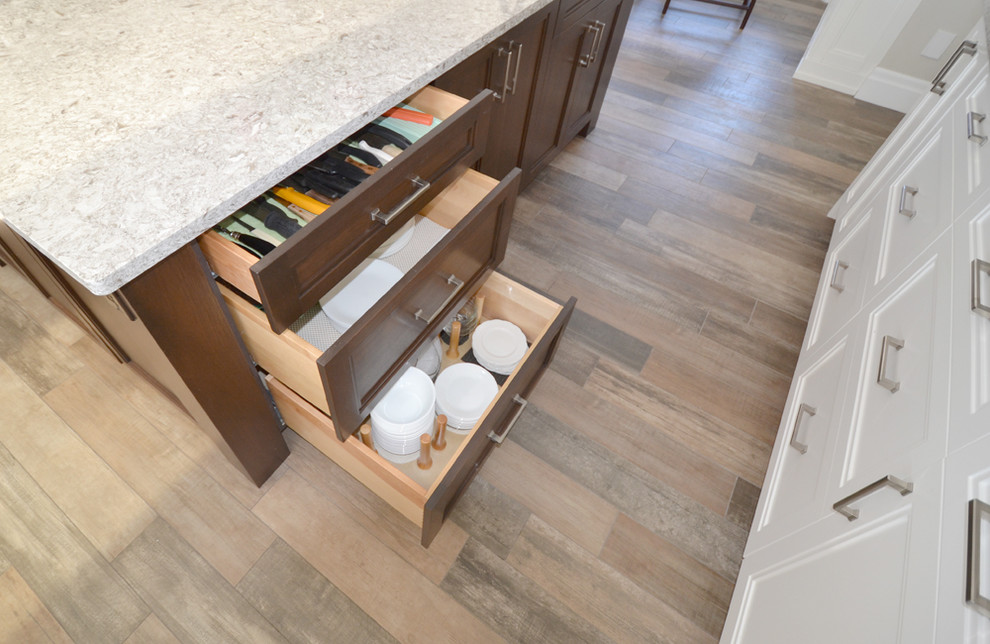 Example of a large transitional l-shaped porcelain tile eat-in kitchen design in Toronto with an undermount sink, shaker cabinets, white cabinets, granite countertops, white backsplash, ceramic backsplash, stainless steel appliances and an island