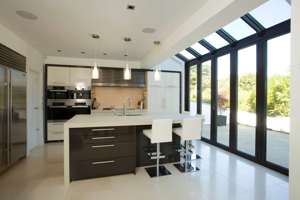 Medium sized contemporary single-wall open plan kitchen in Other with an integrated sink, flat-panel cabinets, quartz worktops, integrated appliances, ceramic flooring, an island, white cabinets, white splashback, marble splashback and white floors.
