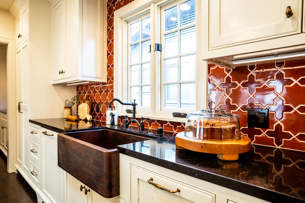 Inredning av ett klassiskt avskilt, mellanstort brun brunt u-kök, med en undermonterad diskho, skåp i shakerstil, vita skåp, granitbänkskiva, flerfärgad stänkskydd, stänkskydd i mosaik, rostfria vitvaror, mörkt trägolv, en köksö och brunt golv