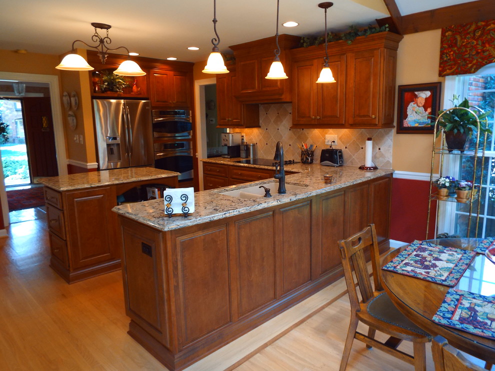 Example of a classic eat-in kitchen design in Louisville with an undermount sink, raised-panel cabinets, quartz countertops and stainless steel appliances