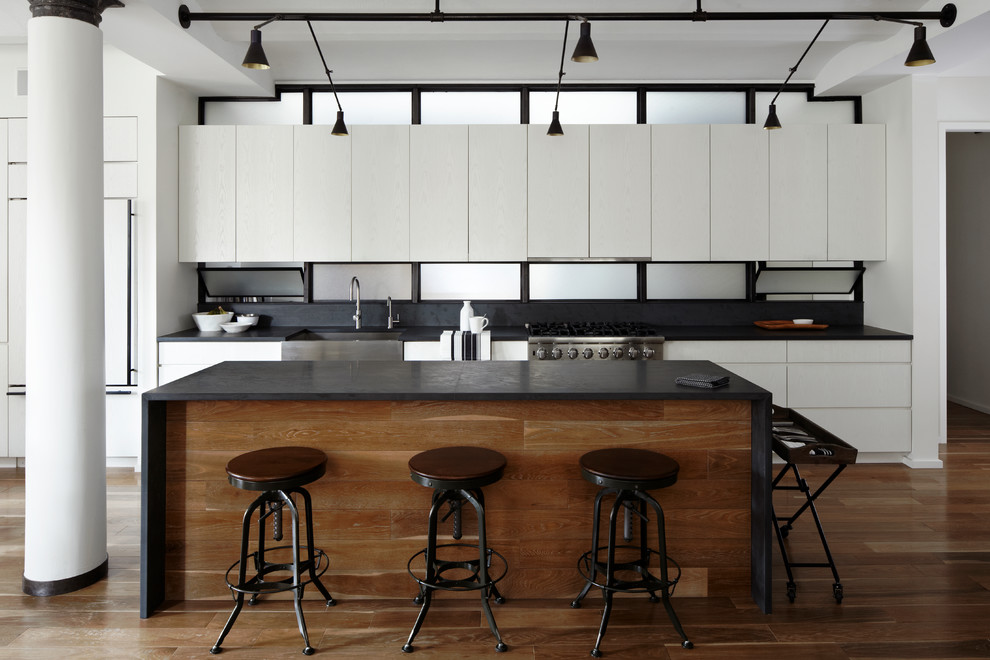 Example of a trendy single-wall open concept kitchen design in New York with a farmhouse sink, flat-panel cabinets and white cabinets