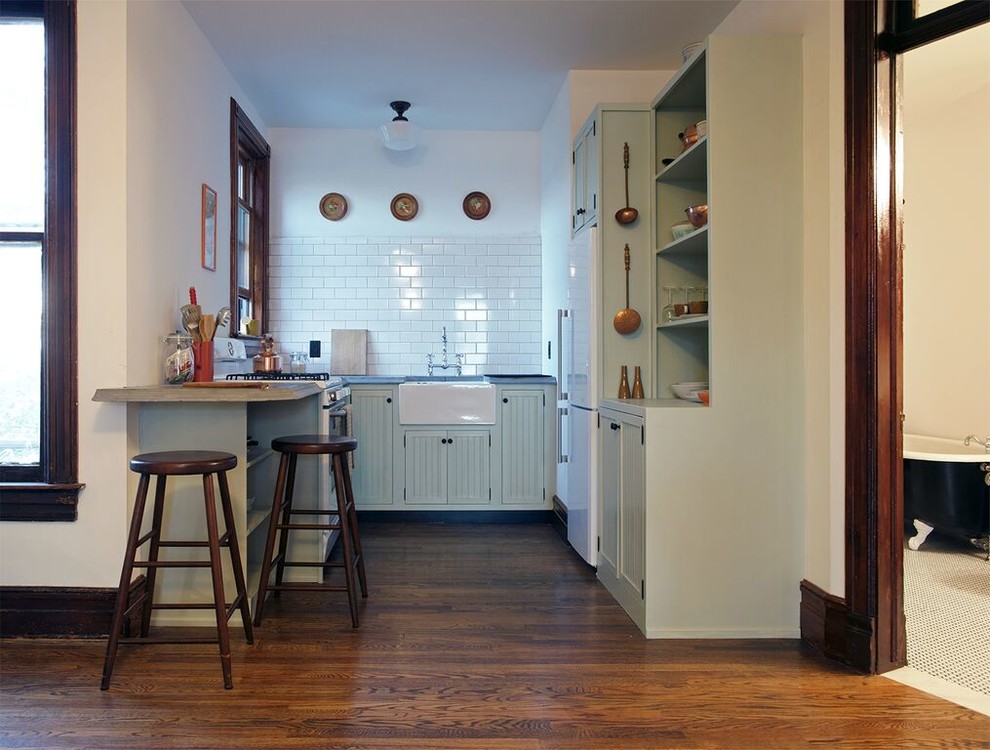Foto på ett stort vintage kök, med en rustik diskho, luckor med lamellpanel, gröna skåp, träbänkskiva, vitt stänkskydd, stänkskydd i stenkakel, vita vitvaror, mörkt trägolv och en halv köksö