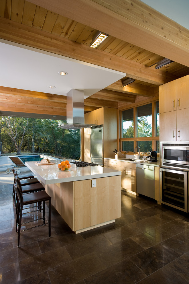 Foto di una cucina moderna di medie dimensioni con elettrodomestici in acciaio inossidabile, lavello sottopiano, ante lisce, ante in legno chiaro e pavimento in pietra calcarea