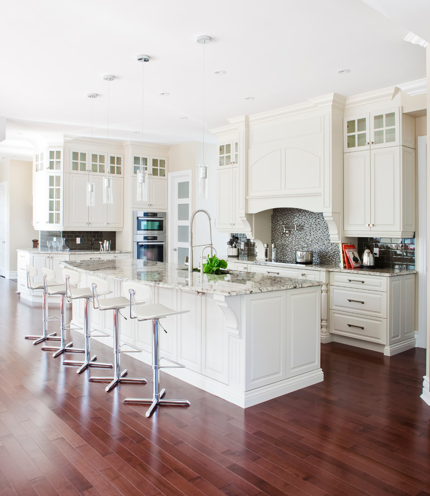 Example of a mid-sized transitional u-shaped medium tone wood floor open concept kitchen design in Montreal with mosaic tile backsplash, stainless steel appliances, recessed-panel cabinets, white cabinets, granite countertops and multicolored backsplash