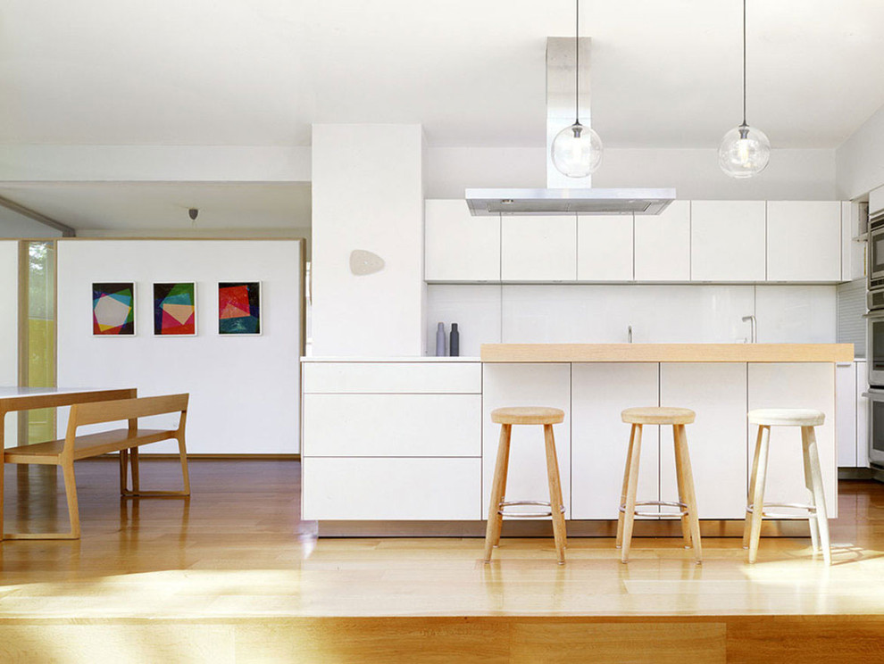 Идея дизайна: параллельная кухня-гостиная среднего размера в стиле модернизм с белыми фасадами, белым фартуком, светлым паркетным полом, плоскими фасадами и столешницей из кварцевого агломерата